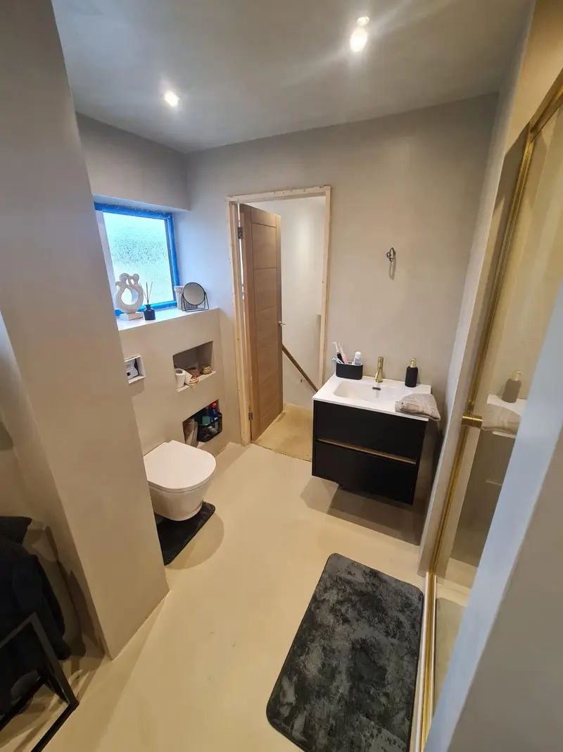 Microcement bathroom with wall-hung toilet, built-in niches and black floating vanity