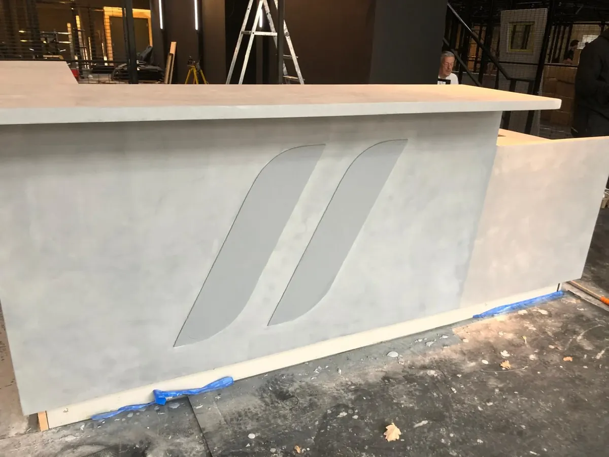 Front of a microcement reception counter with a two-tone inlaid logo