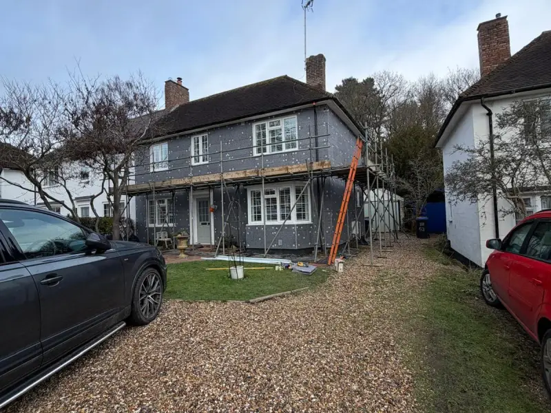 Semi-detached house under scaffolding with grey insulation boards and fixings across the front wall