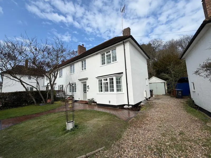 Finished house in bright white silicone render with a black plinth and white windows