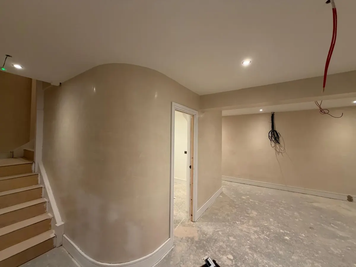 Curved basement wall beside a staircase finished in soft polished Venetian plaster